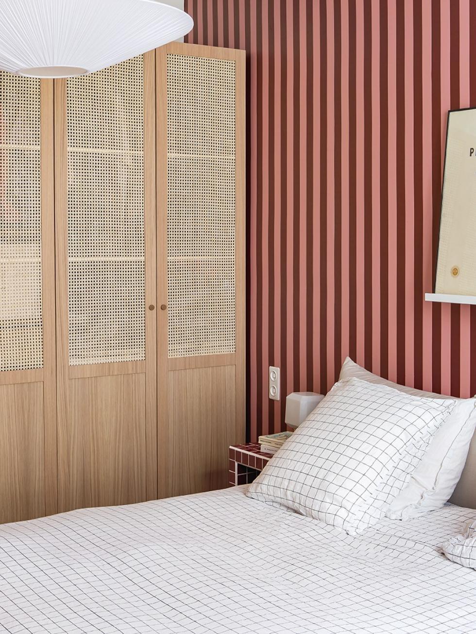 La chambre de Lisa Gachet, avec papier peint bordeau et rose, et un dressing en cannage et en chêne.