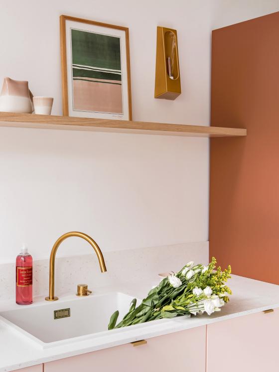A two-tone Fauve and Rose calcaire kitchen with brass details and floating shelf